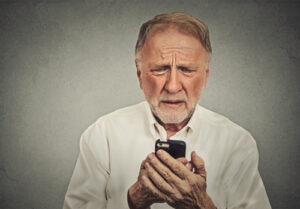 Worried elderly man looking at his smart phone